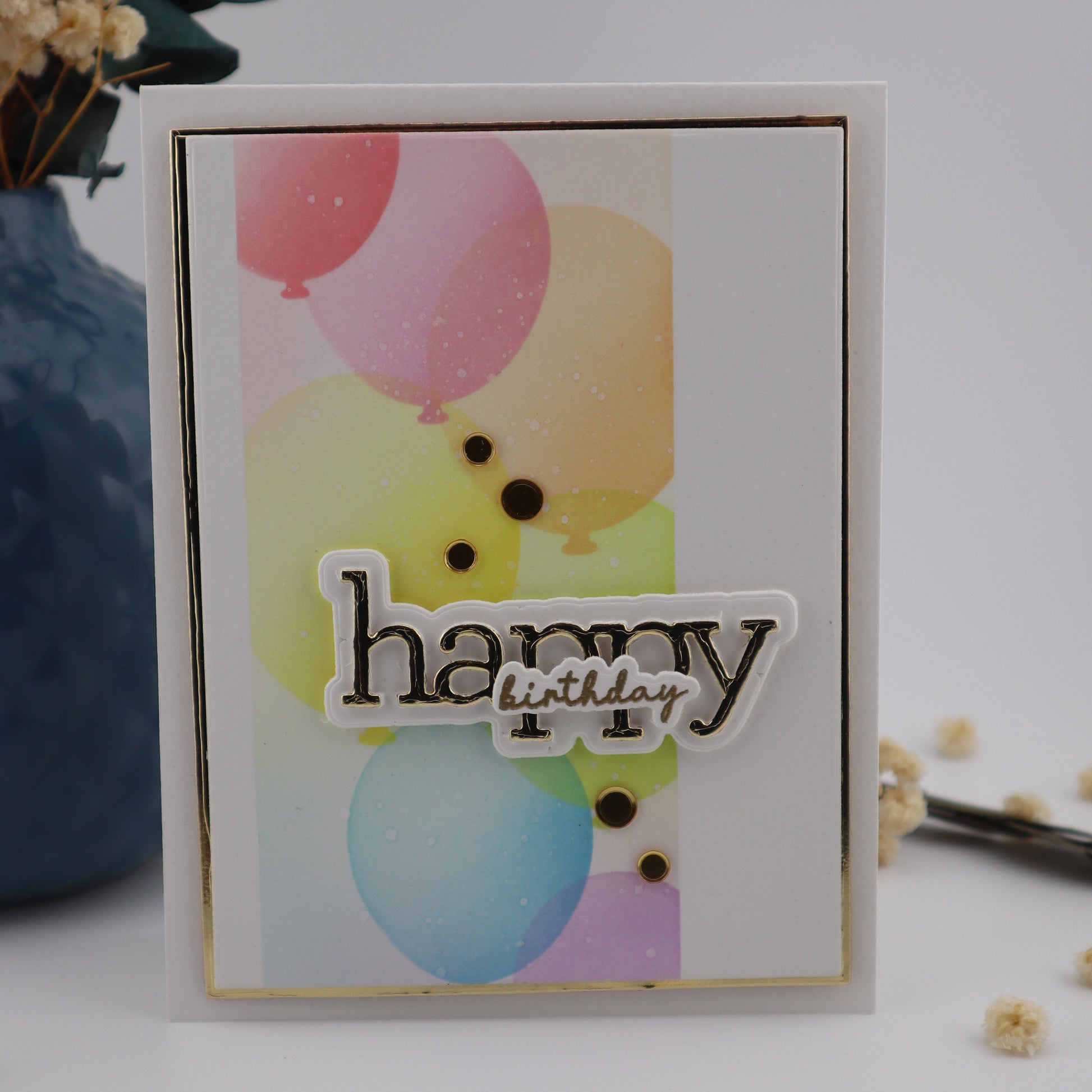 Greeting card with colorful balloons and 'Happy' text on a white background with decorative elements.
