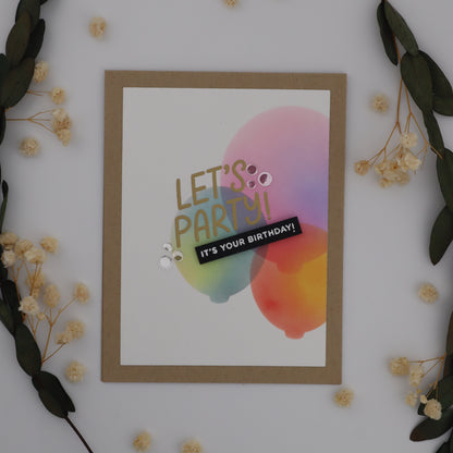 Framed colorful birthday card with 'Let's Party! It's Your Birthday!' text on a white background with decorative elements.