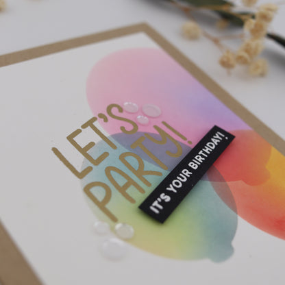 Colorful birthday card with 'Let's Party' text and a small black label saying 'It's Your Birthday'.