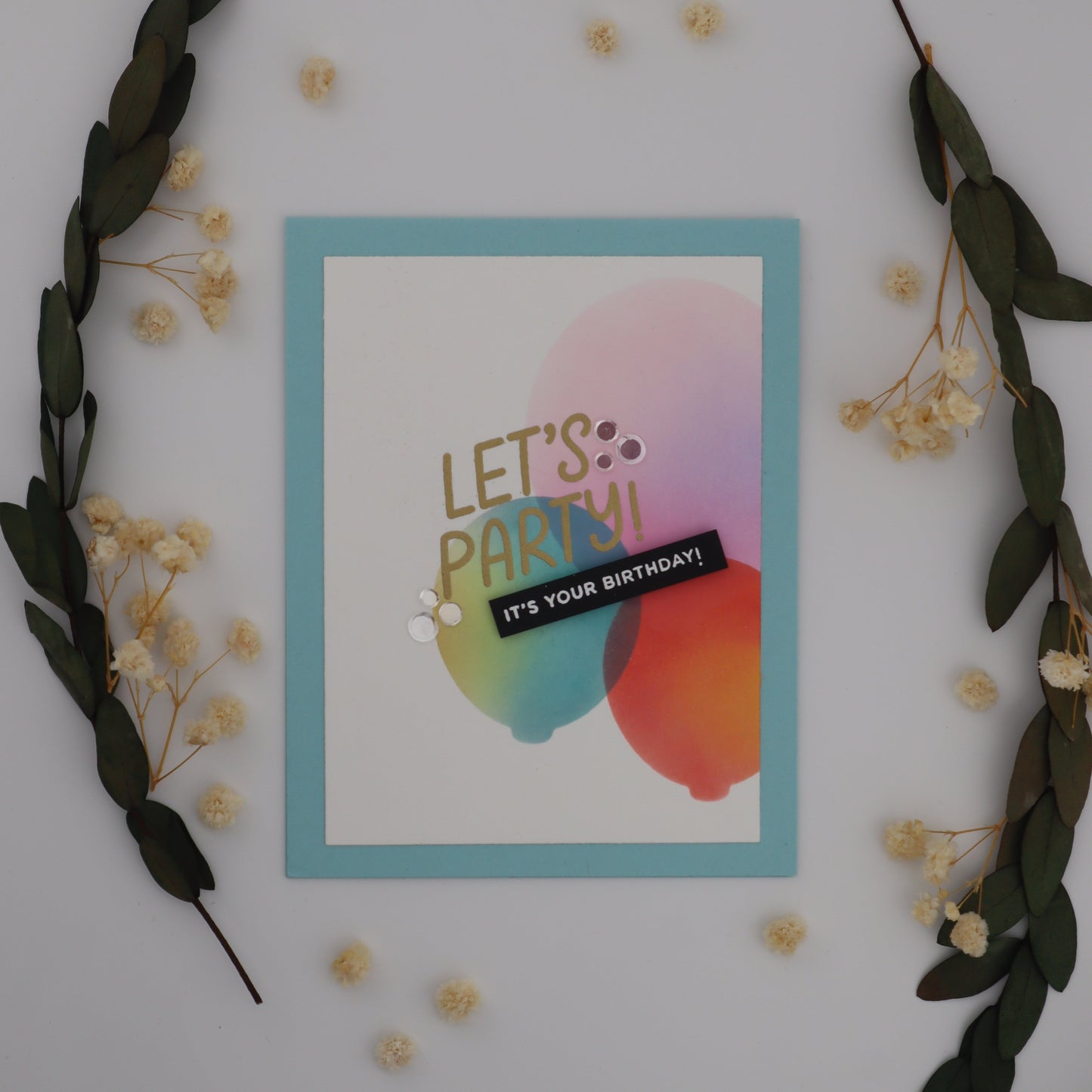 Colorful card with 'Let's Party!' text on a white surface with decorative elements.