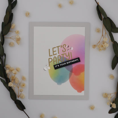 Framed colorful 'Let's Party! It's Your Birthday!' sign on a white wall with decorative elements.