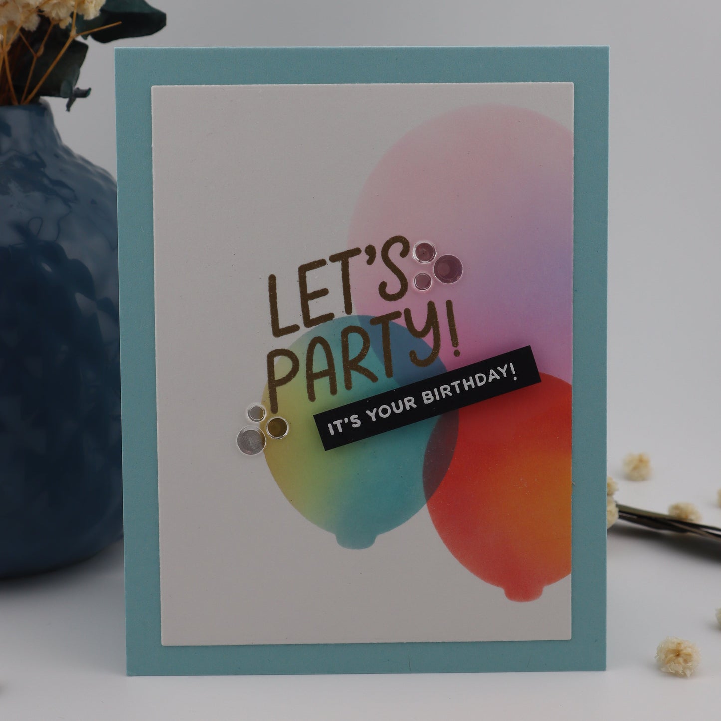 Colorful 'Let's Party' birthday card on a white background with decorative elements.