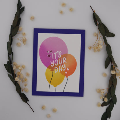 Card with balloons and 'It's Your Day!' text, surrounded by decorative elements on a white background