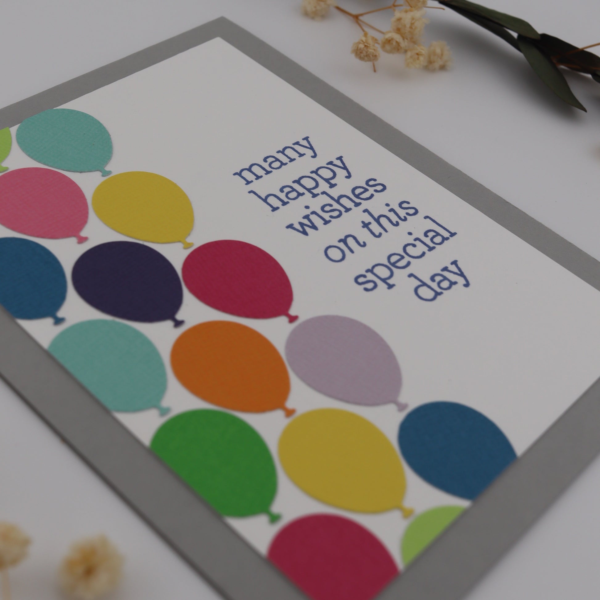 Greeting card with colorful balloons and text on a white background
