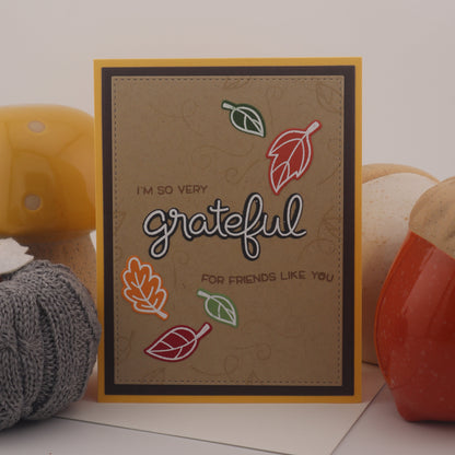 Card with 'grateful' text and autumn leaves on a white background