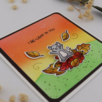 Card with a cartoon bear and leaf design on a white background with dried flowers.