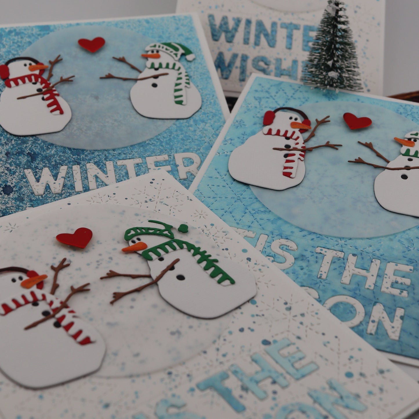 Set of winter-themed cards with snowmen and text on a gray background