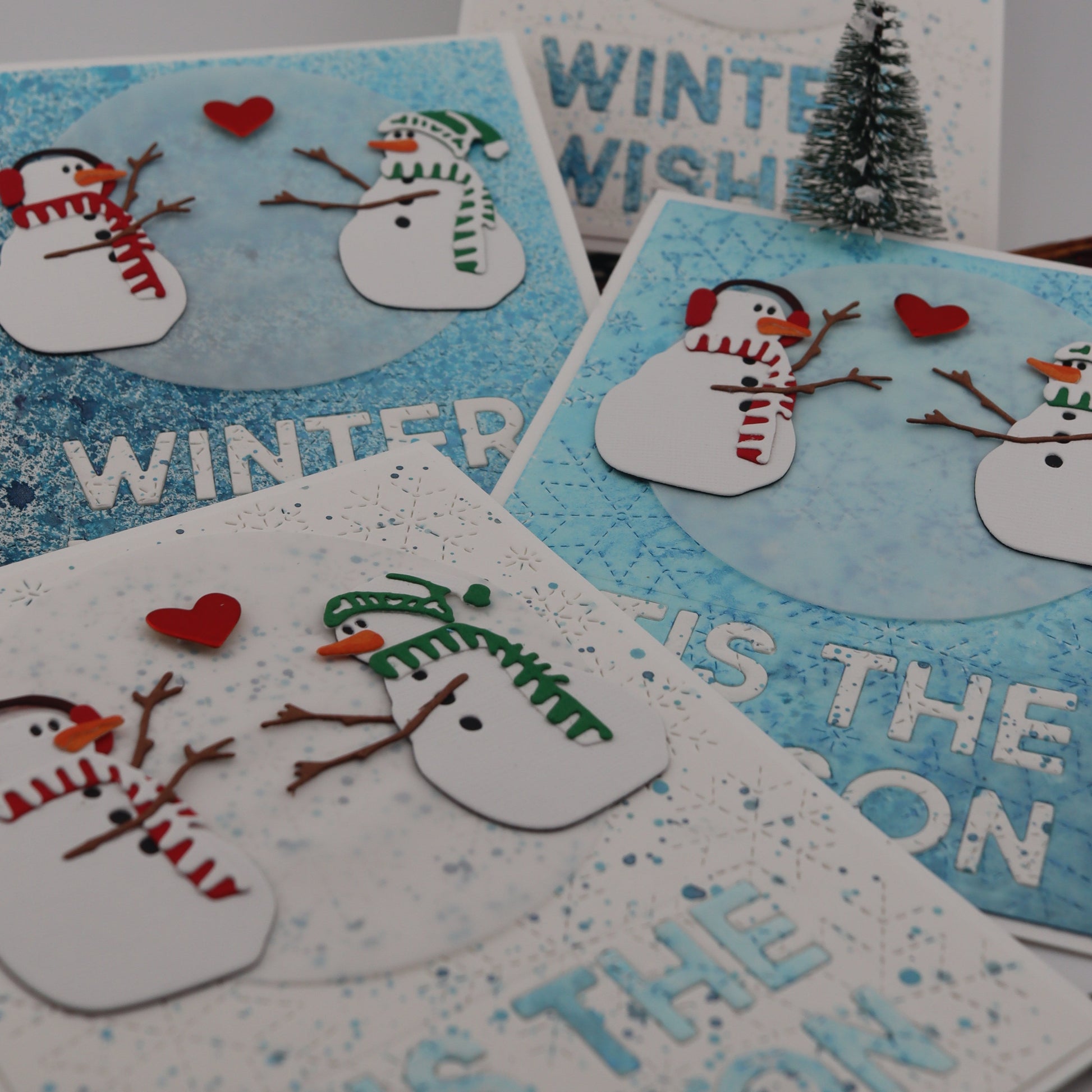 Set of winter-themed cards with snowmen and text on a gray background