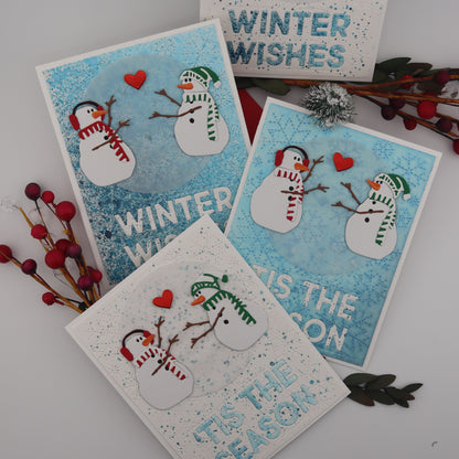 Set of four winter-themed greeting cards with snowmen and text on a white surface.