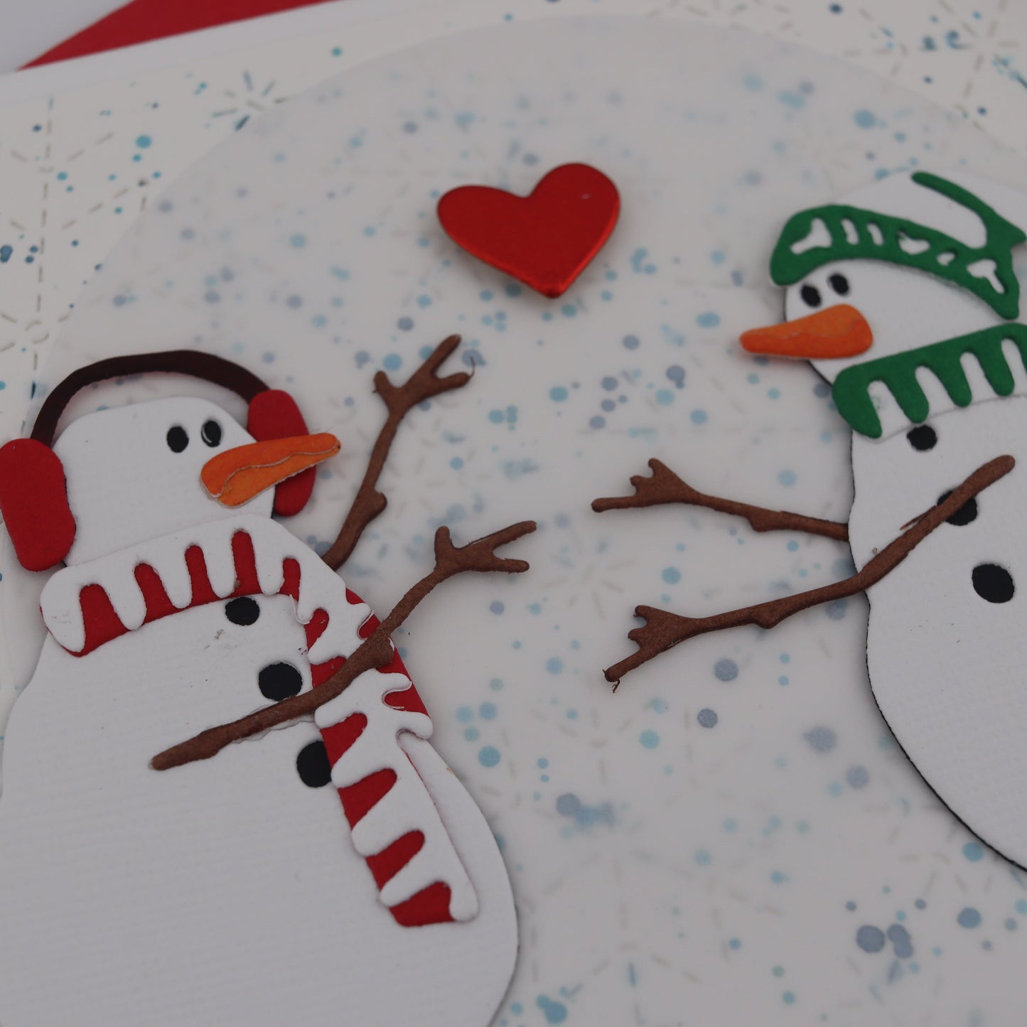 Two snowmen with a red heart on a snowy background