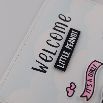 Baby shower card with 'Welcome Little Peanut It's a Girl!' text on a light background.