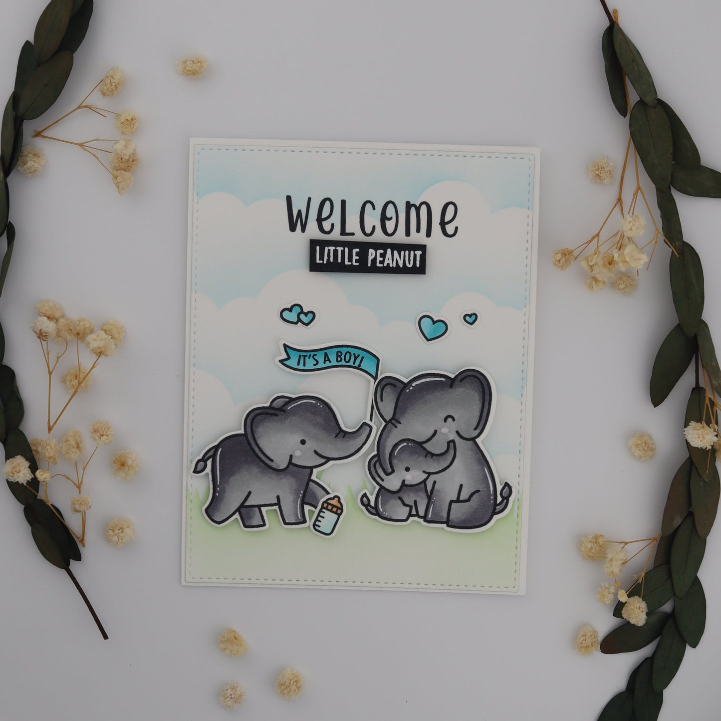 Card with baby elephant illustration and 'Welcome Little Peanut' text on a decorative background with flowers and leaves.