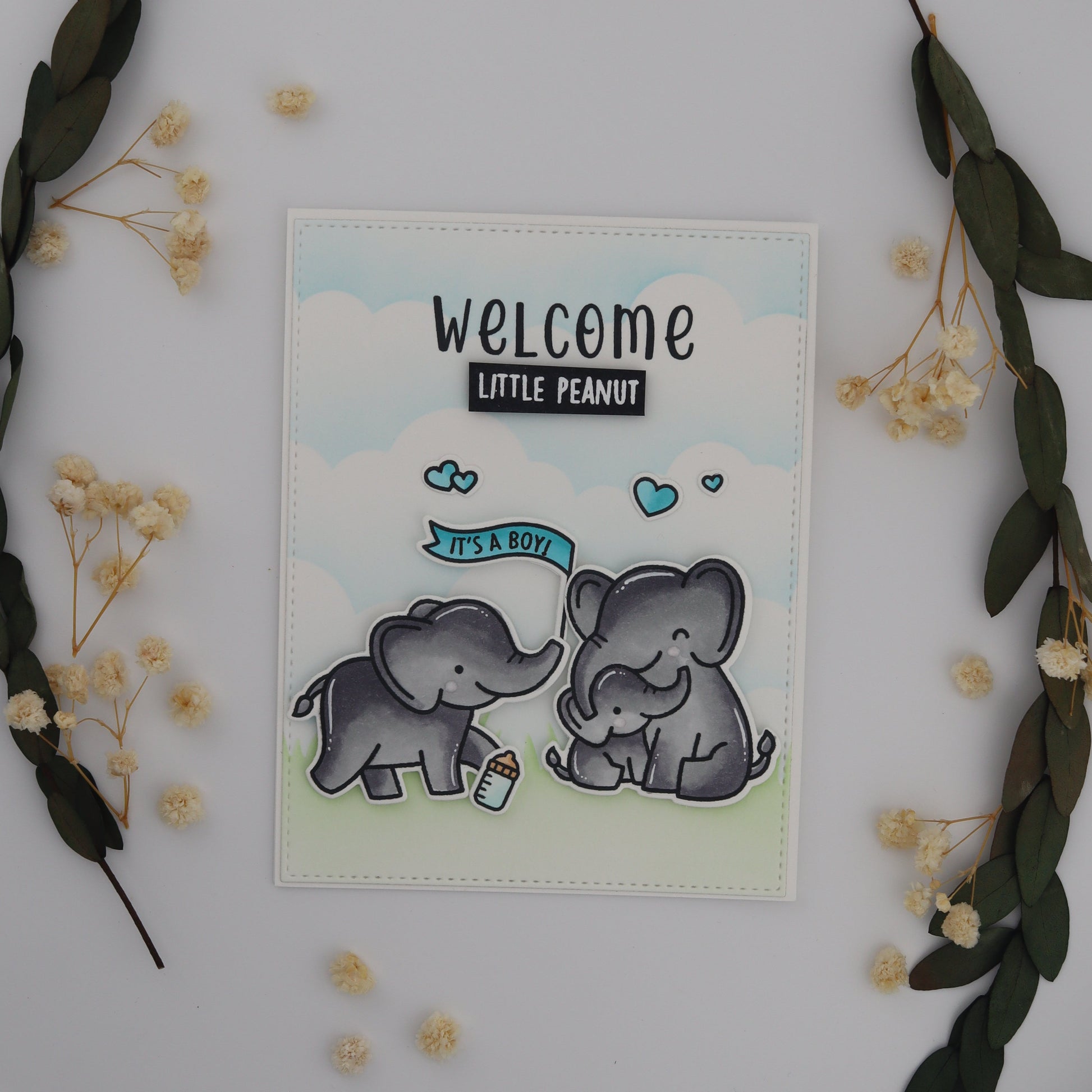 Card with baby elephant illustration and 'Welcome Little Peanut' text on a decorative background with flowers and leaves.