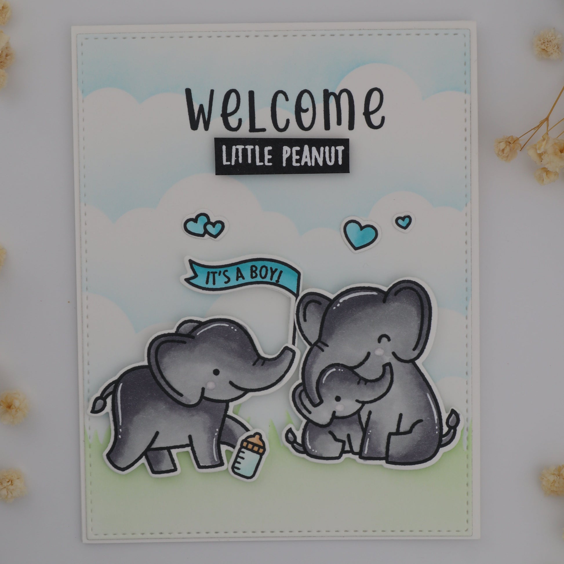 Card with two elephants and 'Welcome Little Peanut' text on a light background with flowers.
