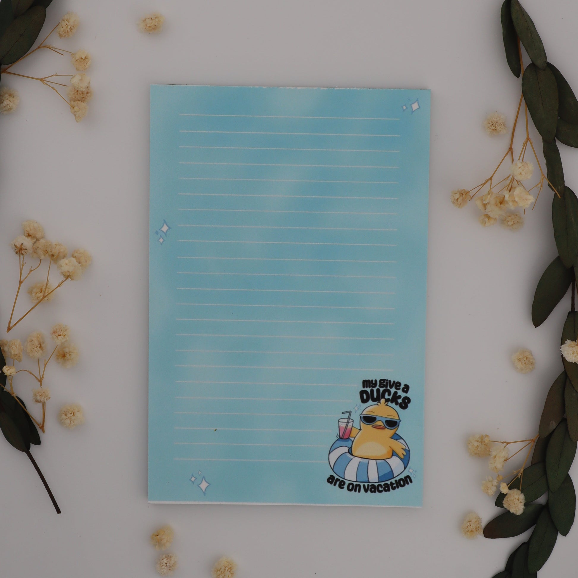 Notepad with cartoon character on a white surface with flowers and leaves