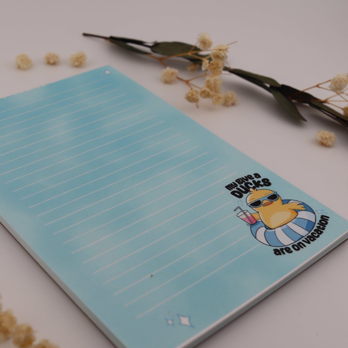Notebook with a cartoon character on a white surface with dried flowers