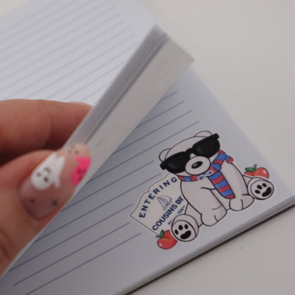 Hand holding a small notepad with a cartoon BEAR design on a white background