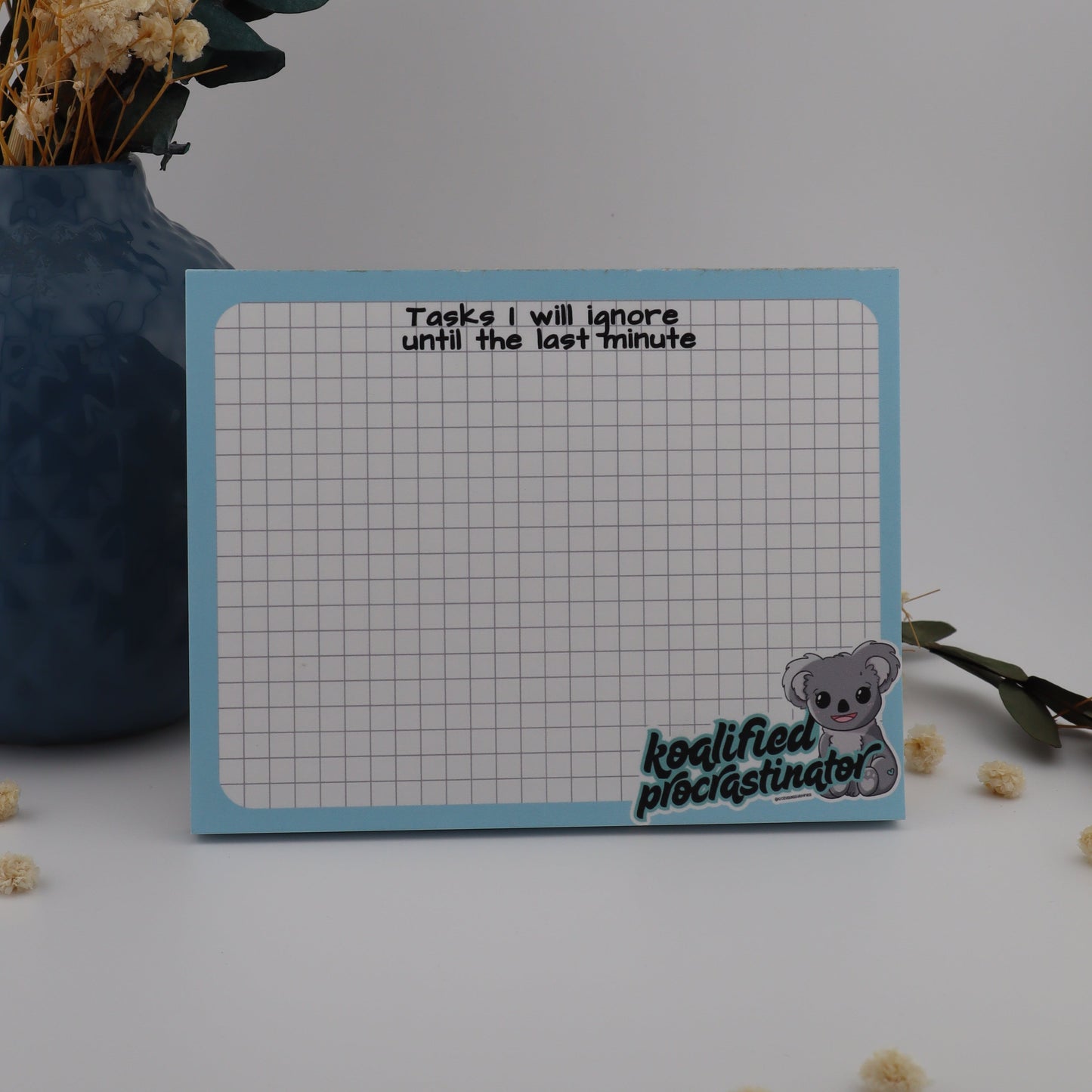 Notebook with grid pattern and text, placed on a surface with decorative elements.