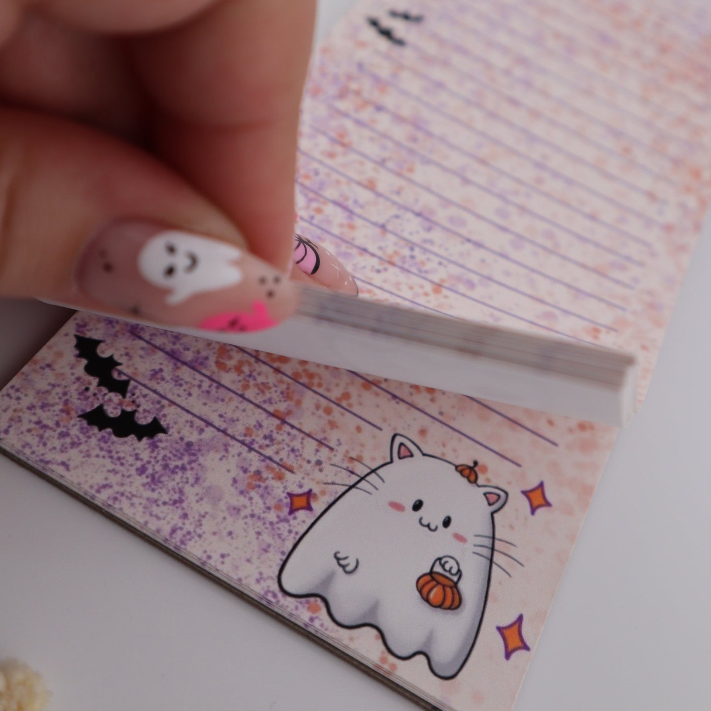 Hand holding a small letter with a cat illustration on a white background