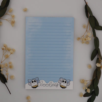 Notepad with cartoon character design on a white surface with decorative elements